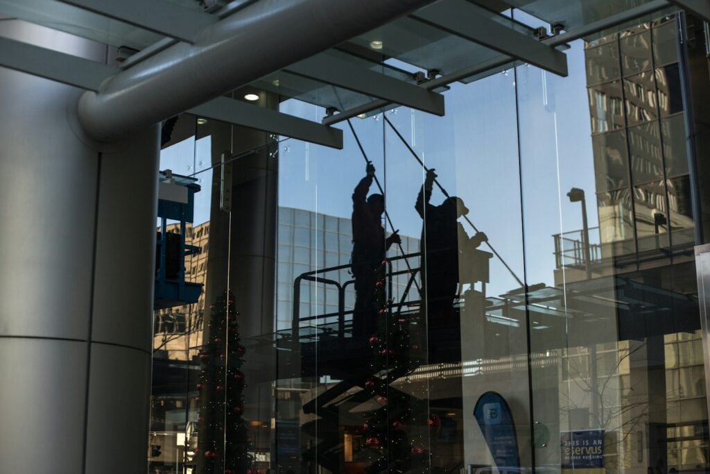 Fachkraft reinigt Glasfenster von einer Hebebühne aus – Glasreinigung durch eine Reinigungsfirma in Berlin