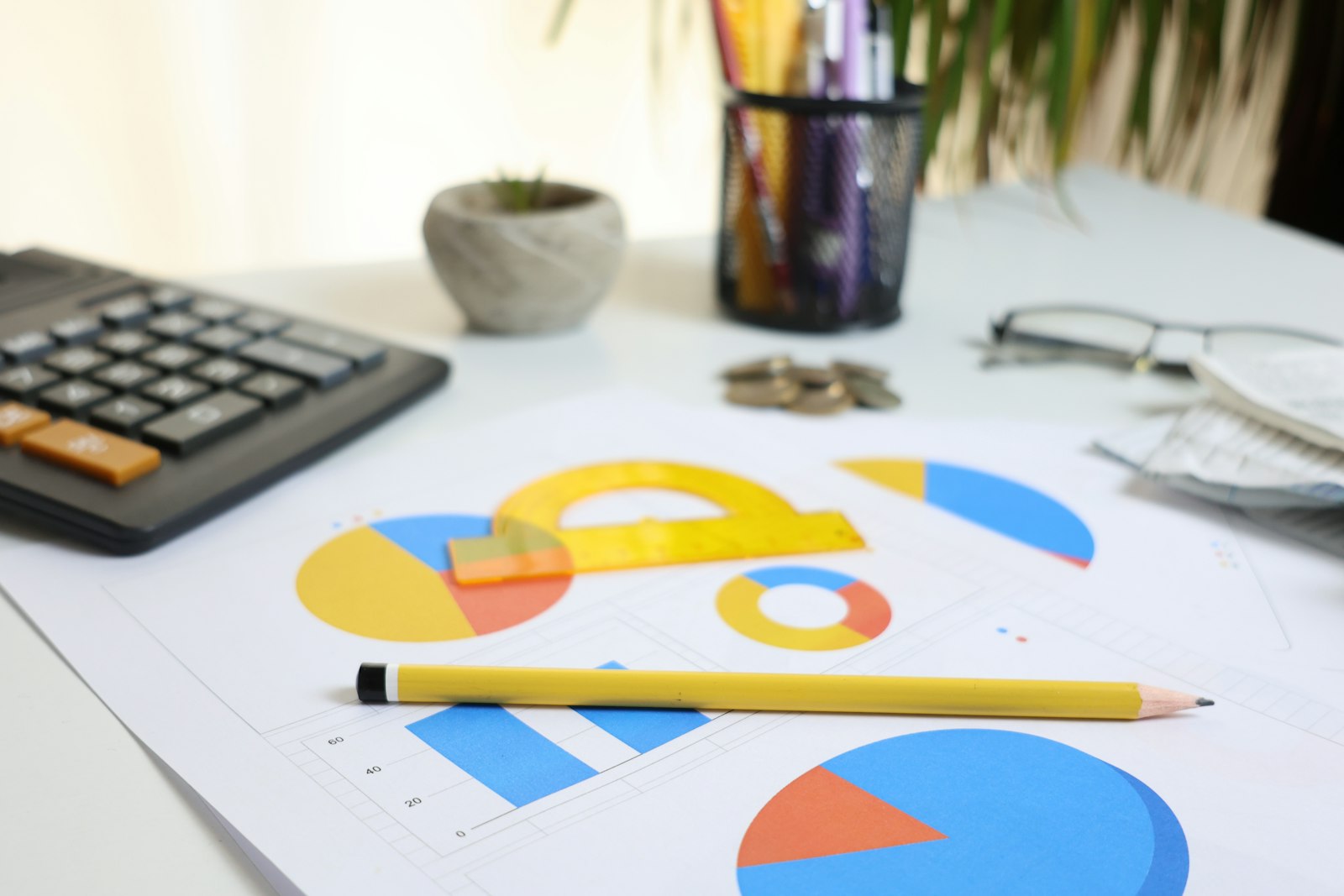 Schreibtisch mit Taschenrechner, Diagrammen und Bleistift beim Erstellen von Finanzplan, Startup-Budget und Prognose