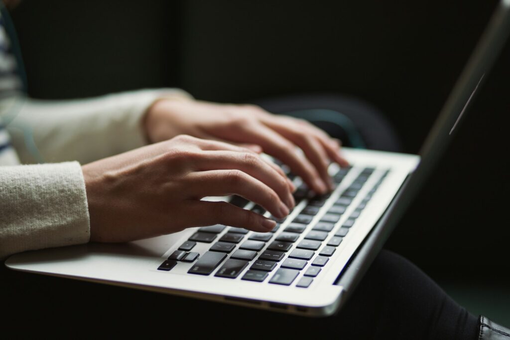 Person am Laptop – ein Kennzeichen reservieren und die Zulassung online vorbereiten