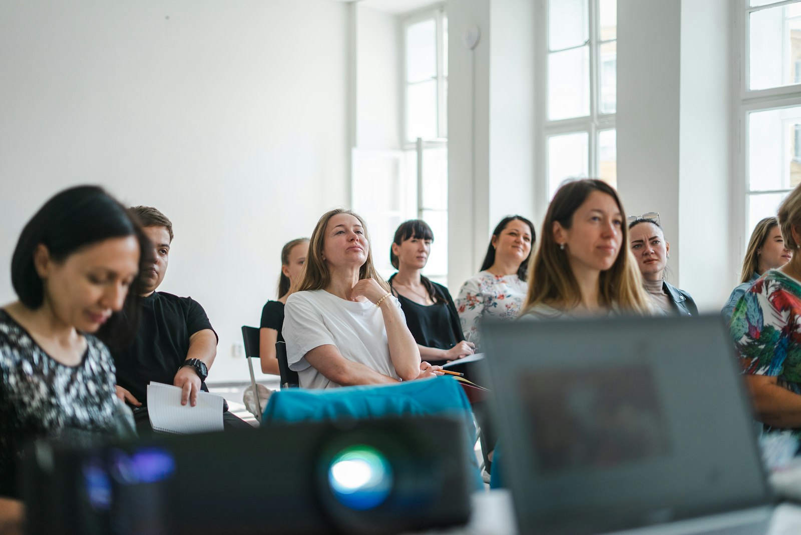 Teilnehmende sitzen in einem hellen Raum bei einem Gründerseminar und hören zu
