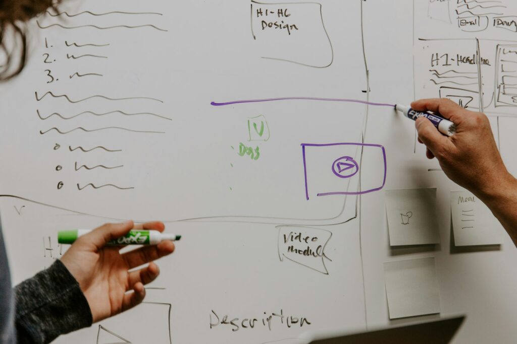 Zwei Personen skizzieren im Workshop Ideen für ein Geschäftsmodell am Whiteboard