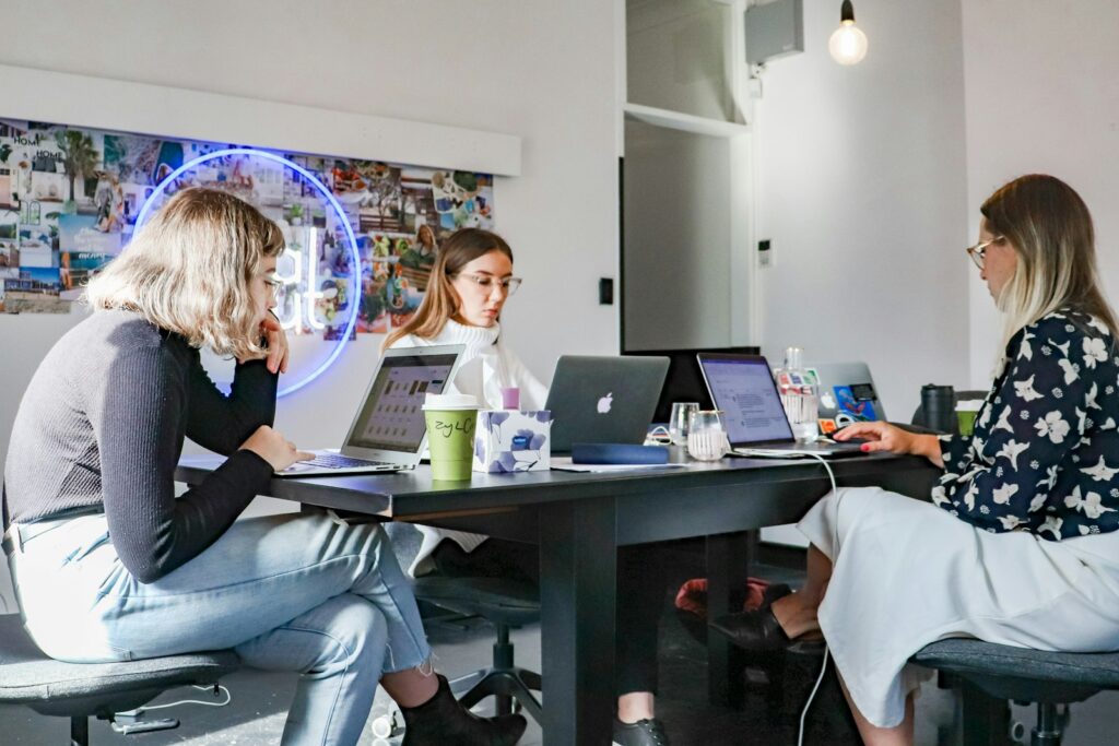 Drei Frauen sitzen mit Laptop am Tisch und besprechen eine Kooperation zur Kundengewinnung