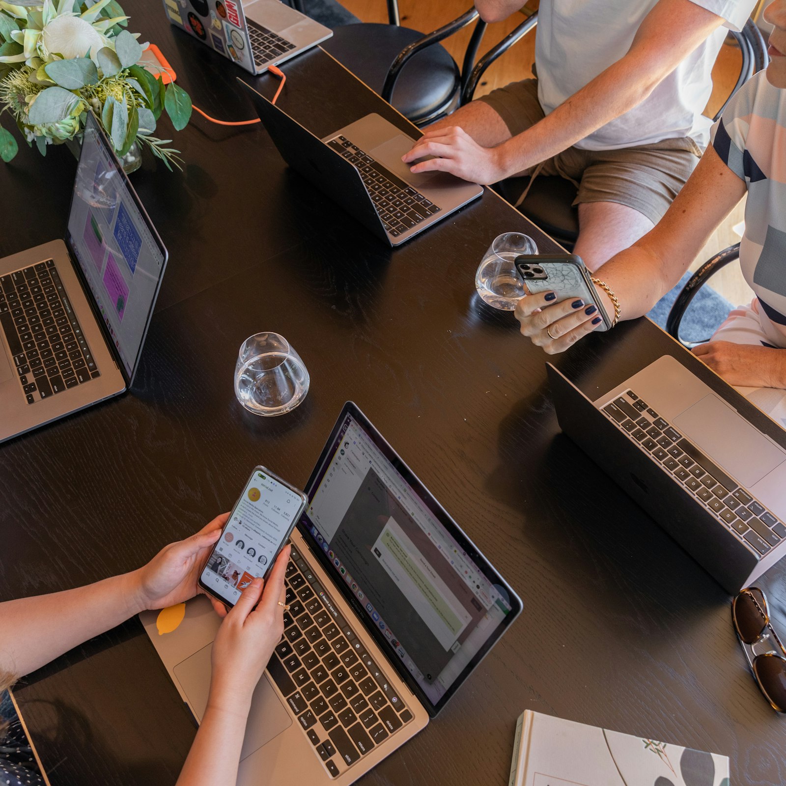 Gründerteam sitzt mit Laptops um einen Tisch und plant Marketing für Startups
