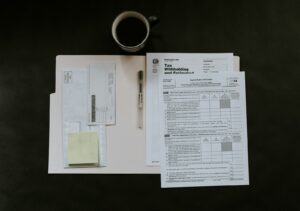 Formulare, Stift und Kaffeetasse auf einem dunklen Schreibtisch für die monatliche Lohnabrechnung