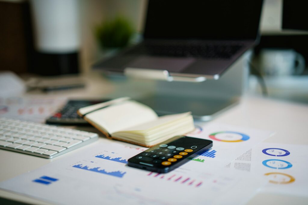 Schreibtisch mit Smartphone und ausgedruckten Finanzdiagrammen zur Liquiditätsplanung