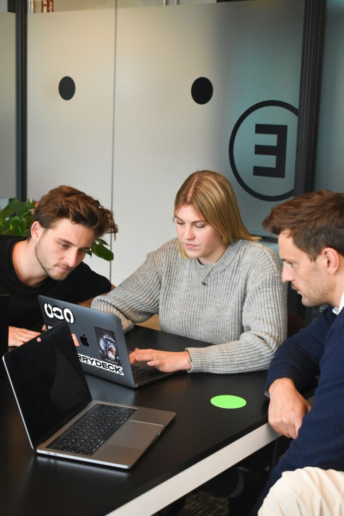 Drei Personen besprechen in einem Büro ein Projekt am Laptop mit ihrer Webflow Agentur