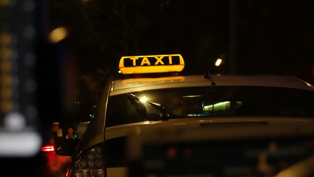 Taxi fährt bei Nacht durch eine beleuchtete Straße