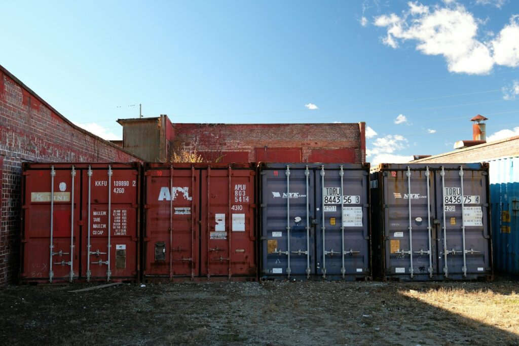 Mehrere Lagercontainer stehen aufgereiht vor Backsteingebäuden in einem Gewerbehof