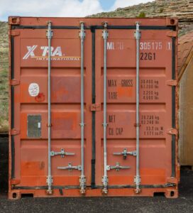 Orangefarbener Lagercontainer auf einem Schotterplatz – wer einen Seecontainer kaufen will, braucht einen festen Stellplatz