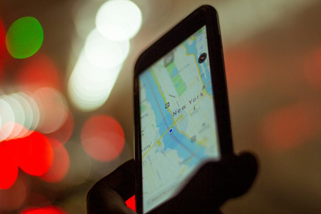 Person hält ein Smartphone mit Kartenansicht und plant den nächsten Termin unterwegs
