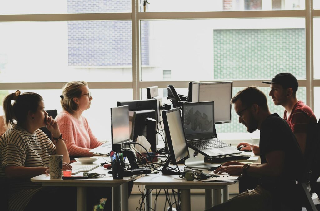 Team einer SaaS Agentur arbeitet gemeinsam an Computern in einem hellen Büro