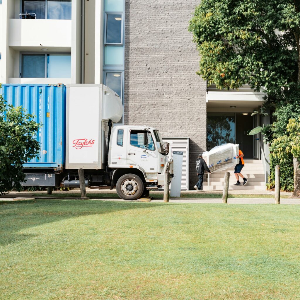 Umzugsunternehmen Berlin: Umzugswagen vor einem Wohnhaus, eine Person trägt Möbel