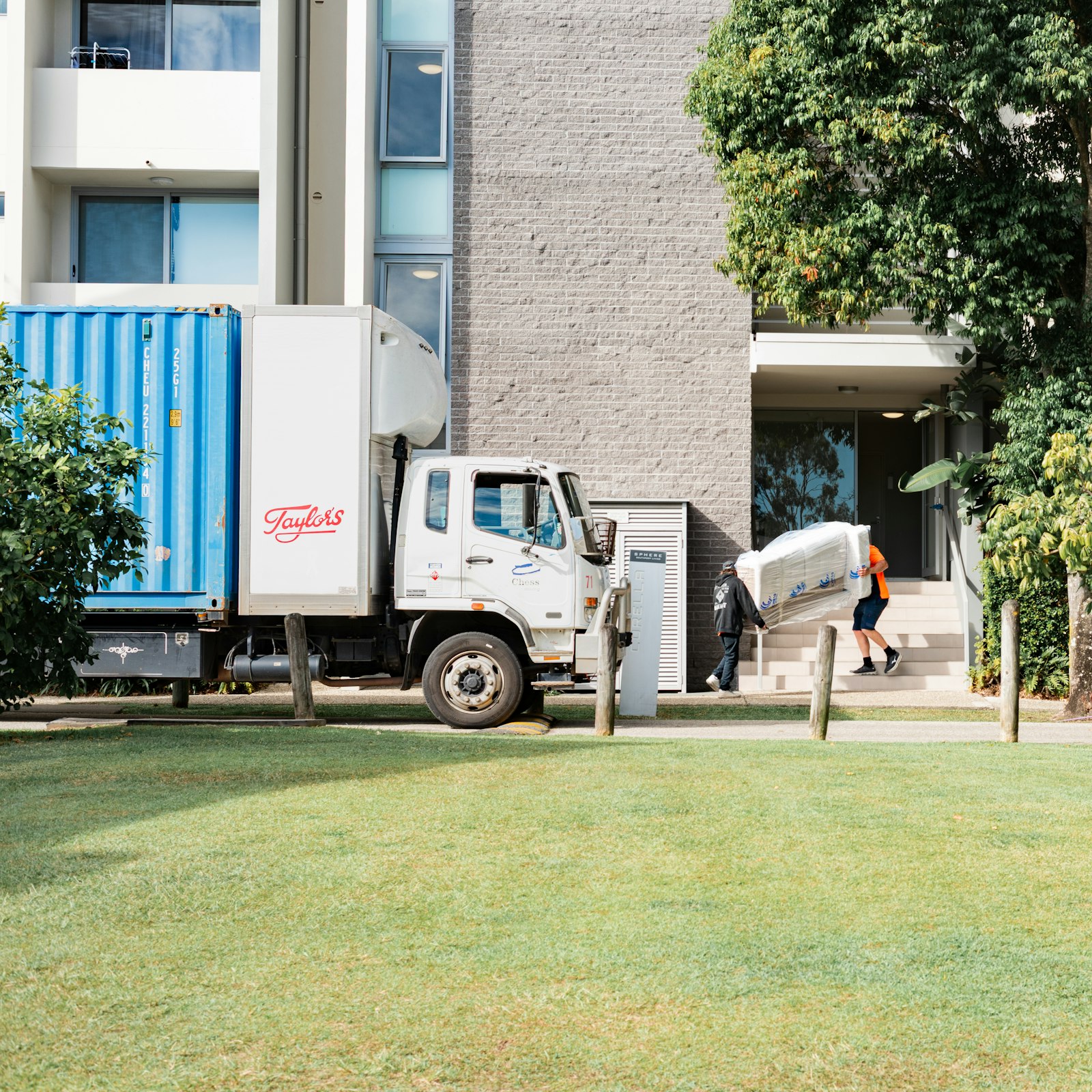 Umzugsunternehmen Berlin: Umzugswagen vor einem Wohnhaus, eine Person trägt Möbel