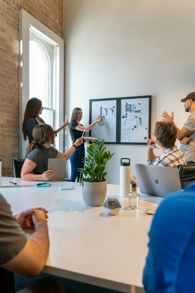 Gruppe von Menschen bespricht an einem weißen Tisch Prozesse und Verantwortlichkeiten im Startup