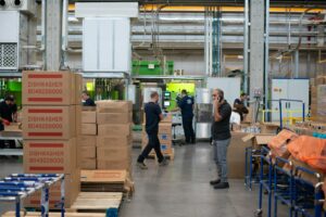 Gründer steht neben gestapelten Versandkartons – Pre-Orders und erste Bestellungen im E-Commerce-Startup