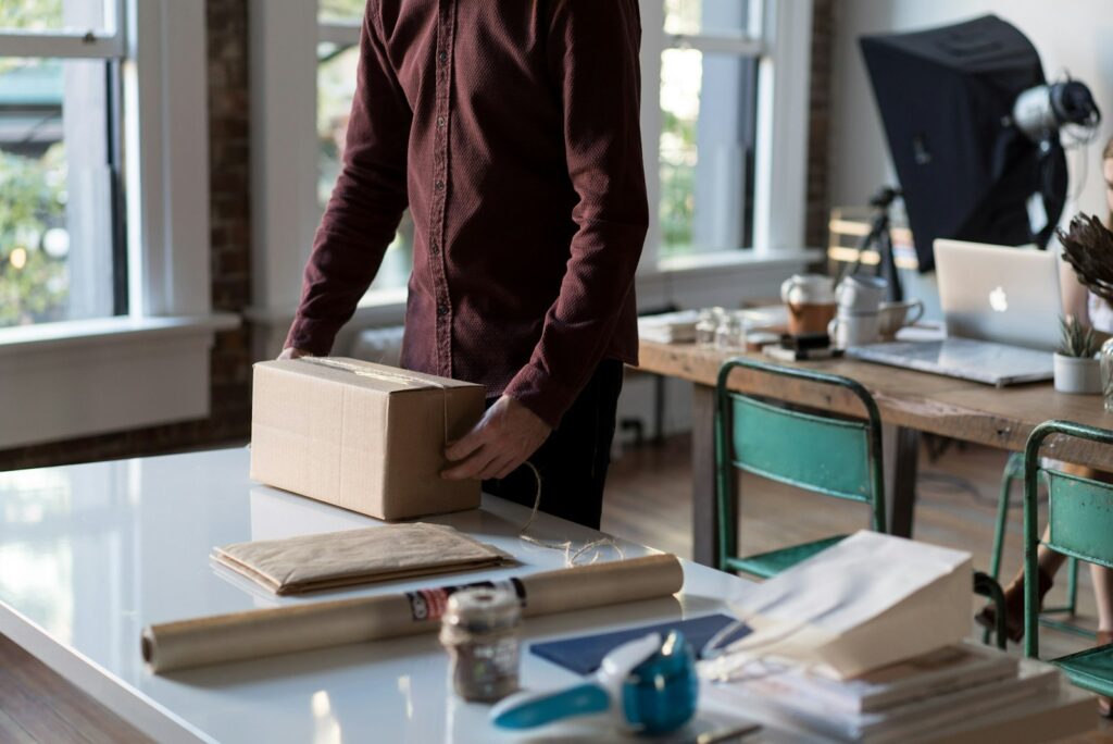 Person hält einen verpackten Versandkarton für die erste Kundenbestellung