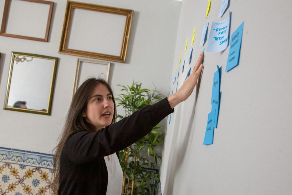 Frau schreibt im Workshop Ideen auf Haftnotizen an einer Wand