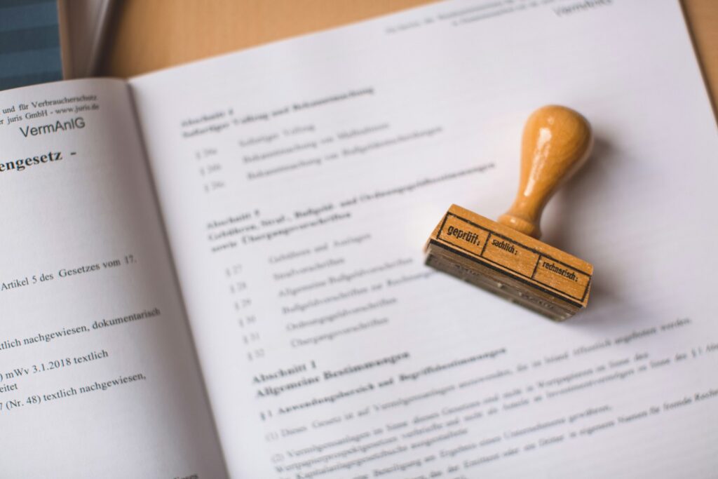 Holzstempel liegt auf einem offenen deutschen Rechtsdokument neben einer beglaubigten Übersetzung
