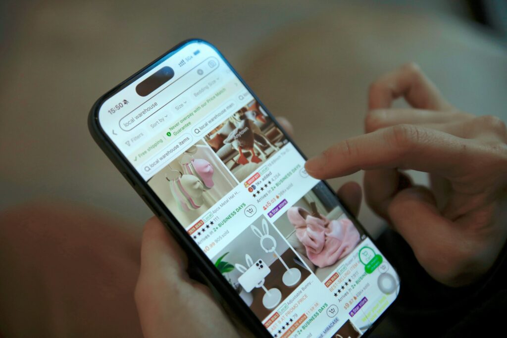 Person scrollt auf dem Smartphone durch einen Onlineshop