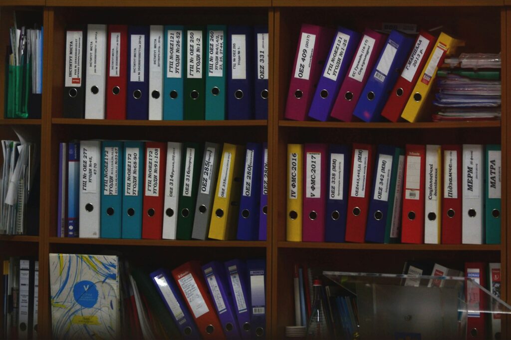 Bunte Ordner in einem Büroregal mit Unterlagen zur Lohnabrechnung und Aufbewahrung