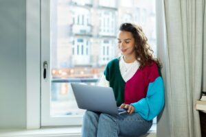 Freelancer arbeitet mit Laptop auf einer Fensterbank
