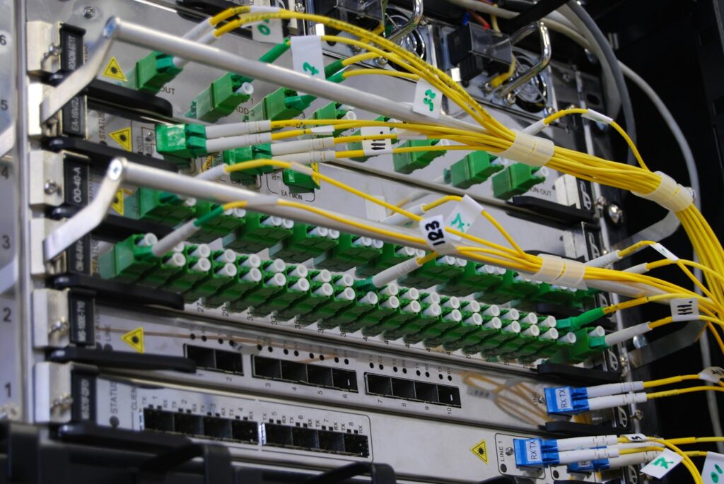 Glasfaserkabel an einem Netzwerk-Switch im Serverrack, auf dem DNS und Domains technisch aufsetzen
