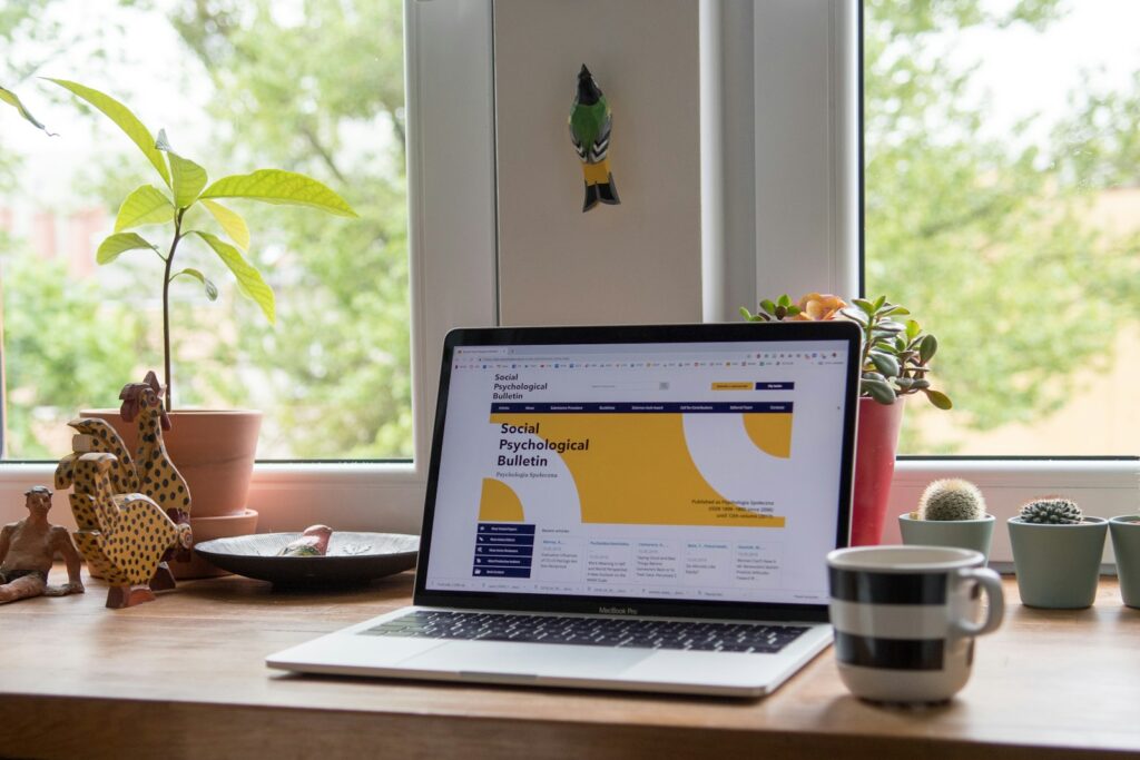 Laptop mit geöffneter Website auf einem Holzschreibtisch, Symbolbild für Website selbst erstellen im Startup