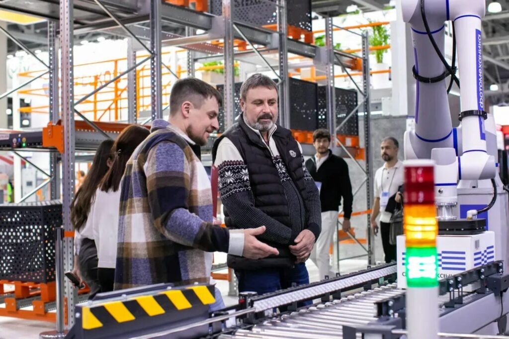 Mitarbeiter beobachten ein automatisiertes Förderbandsystem in der Intralogistik eines Lagers