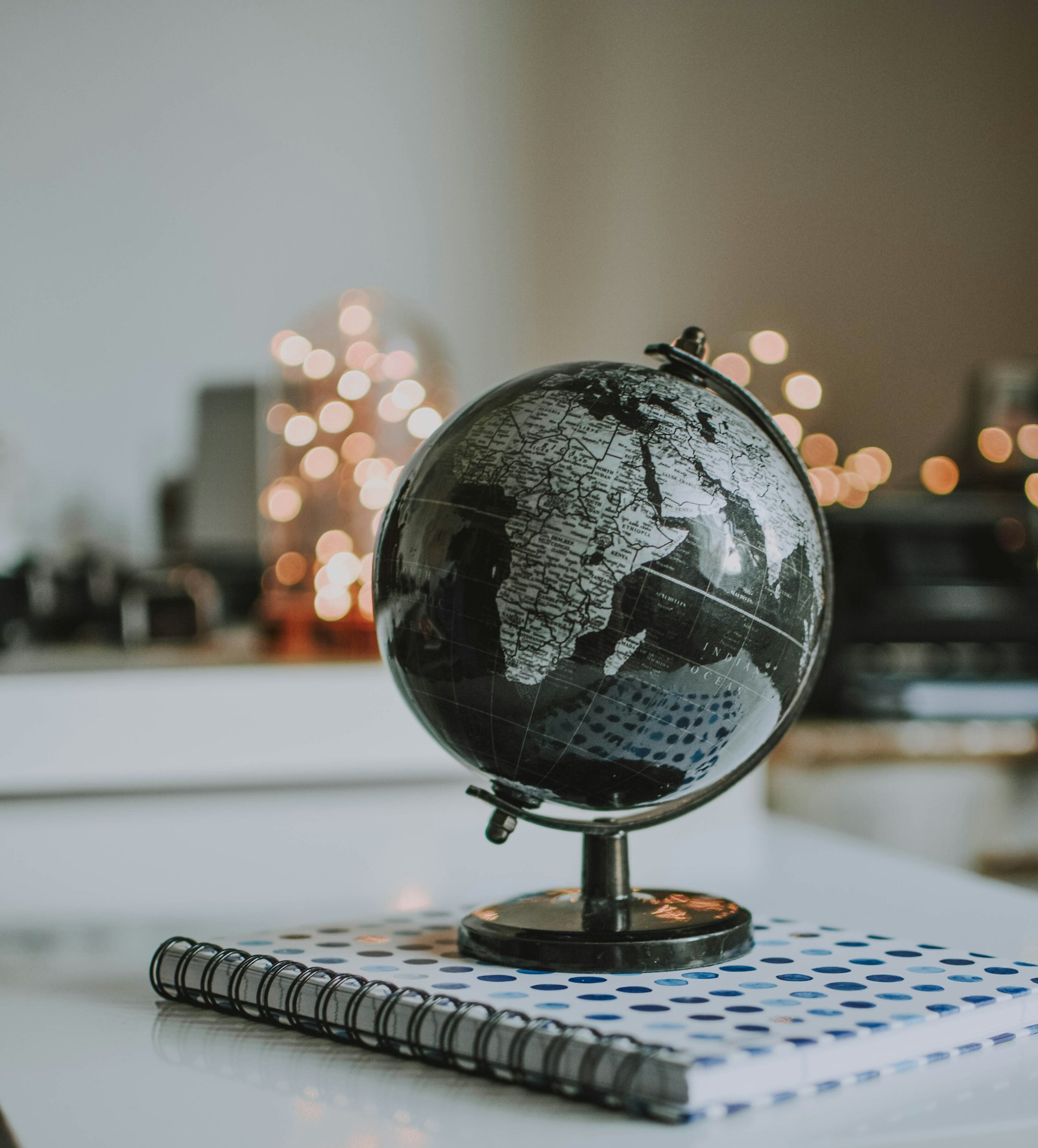 Schreibtischglobus auf einem Notizbuch als Sinnbild für internationale Domains und Expansion
