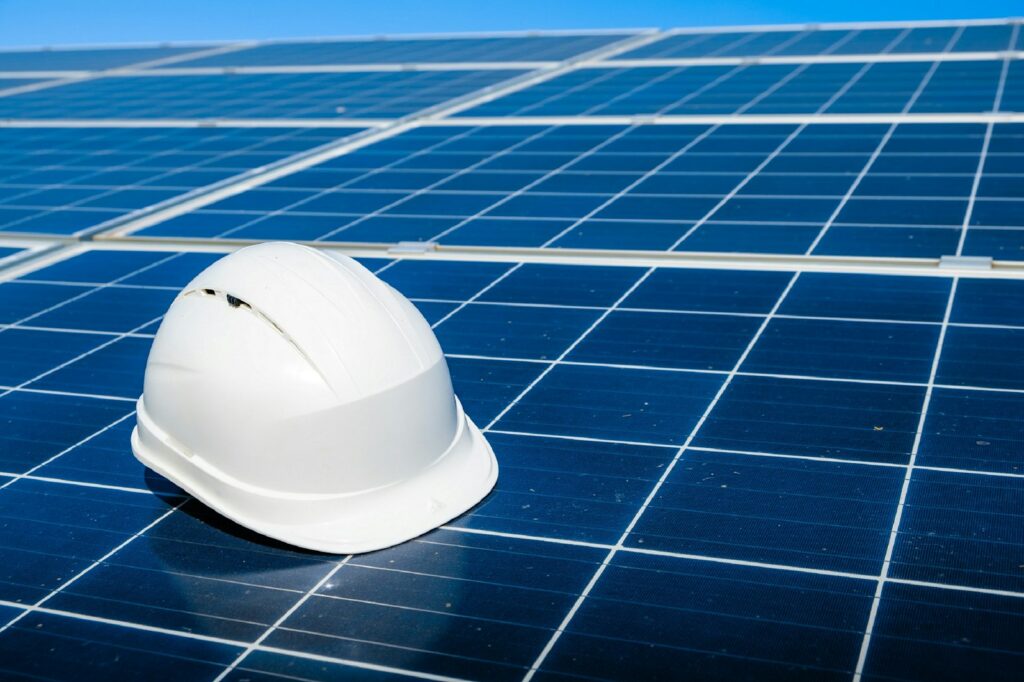 Weißer Schutzhelm liegt auf einem Solarmodul als Symbol für Wartung und Betrieb