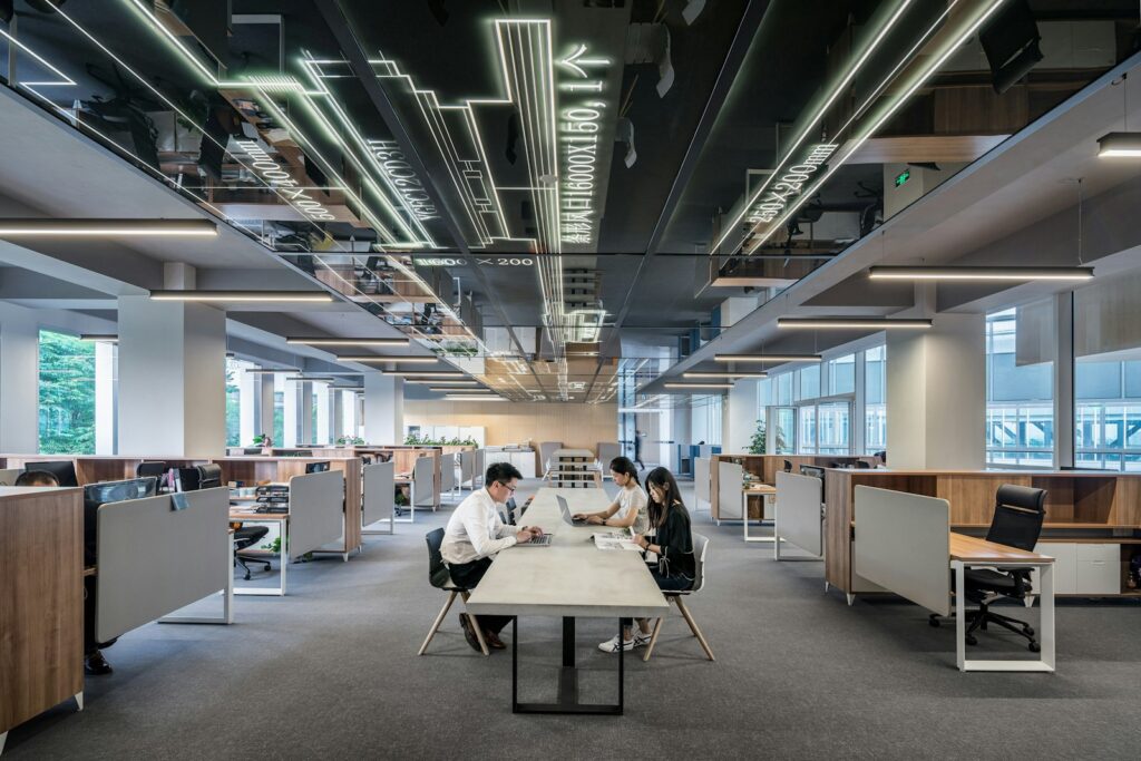 Drei Personen arbeiten gemeinsam in einem offenen Büro mit Schreibtischen