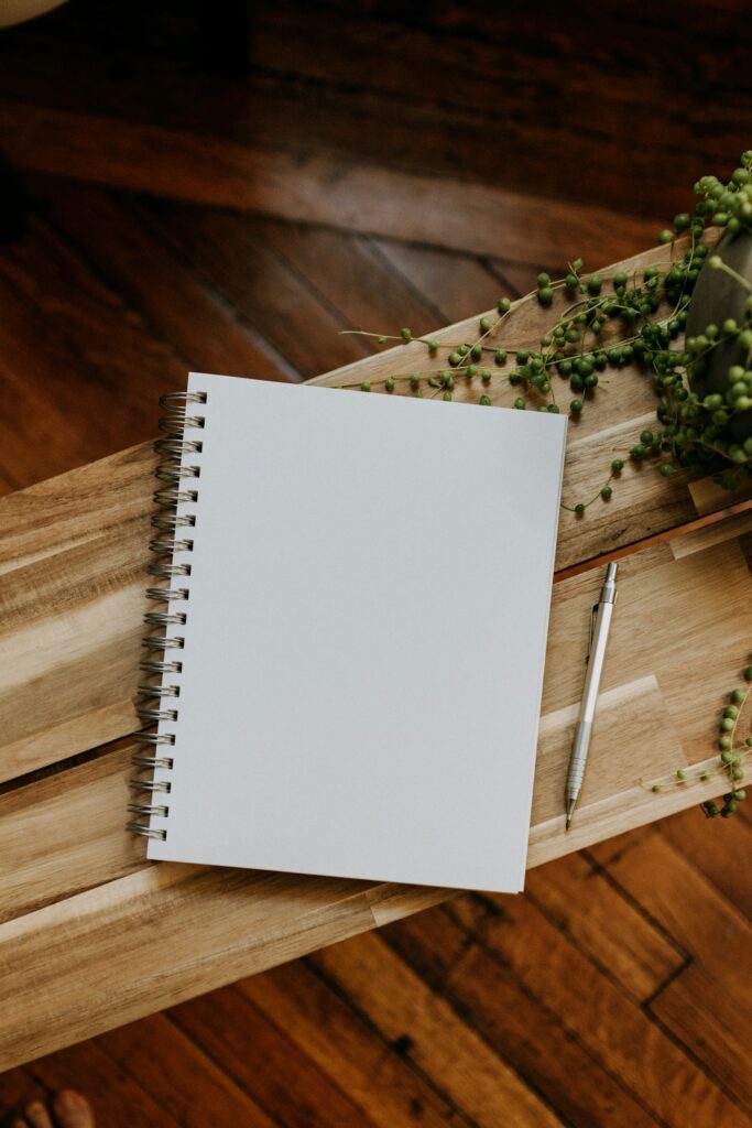 Notizbuch und Stift auf einem Holztisch als Beispiel für nützliche Werbeartikel