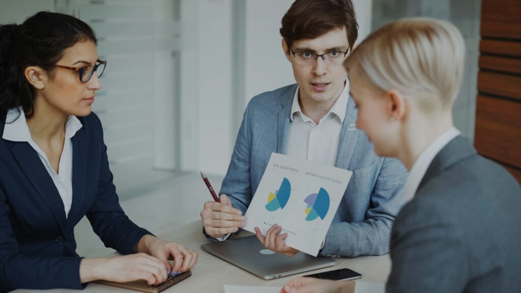 Drei Fachleute besprechen Diagramme mit Kennzahlen aus der Vertriebspipeline