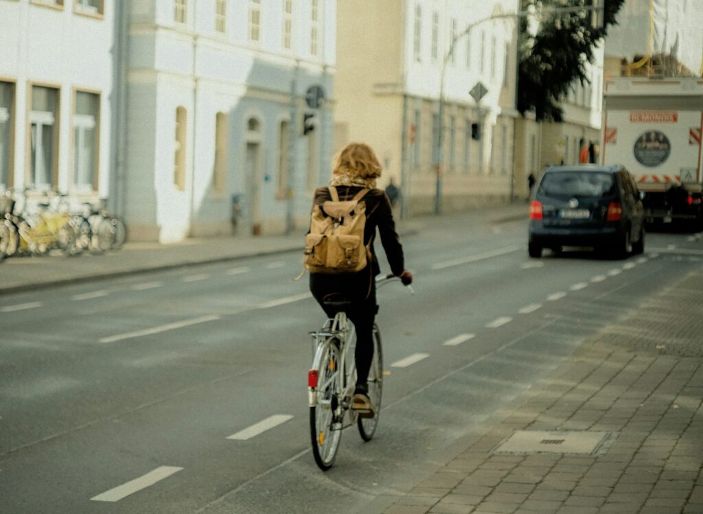 Frau fährt mit dem Fahrrad auf einer Straße zur Arbeit, Beispiel für ein Dienstrad als Benefit