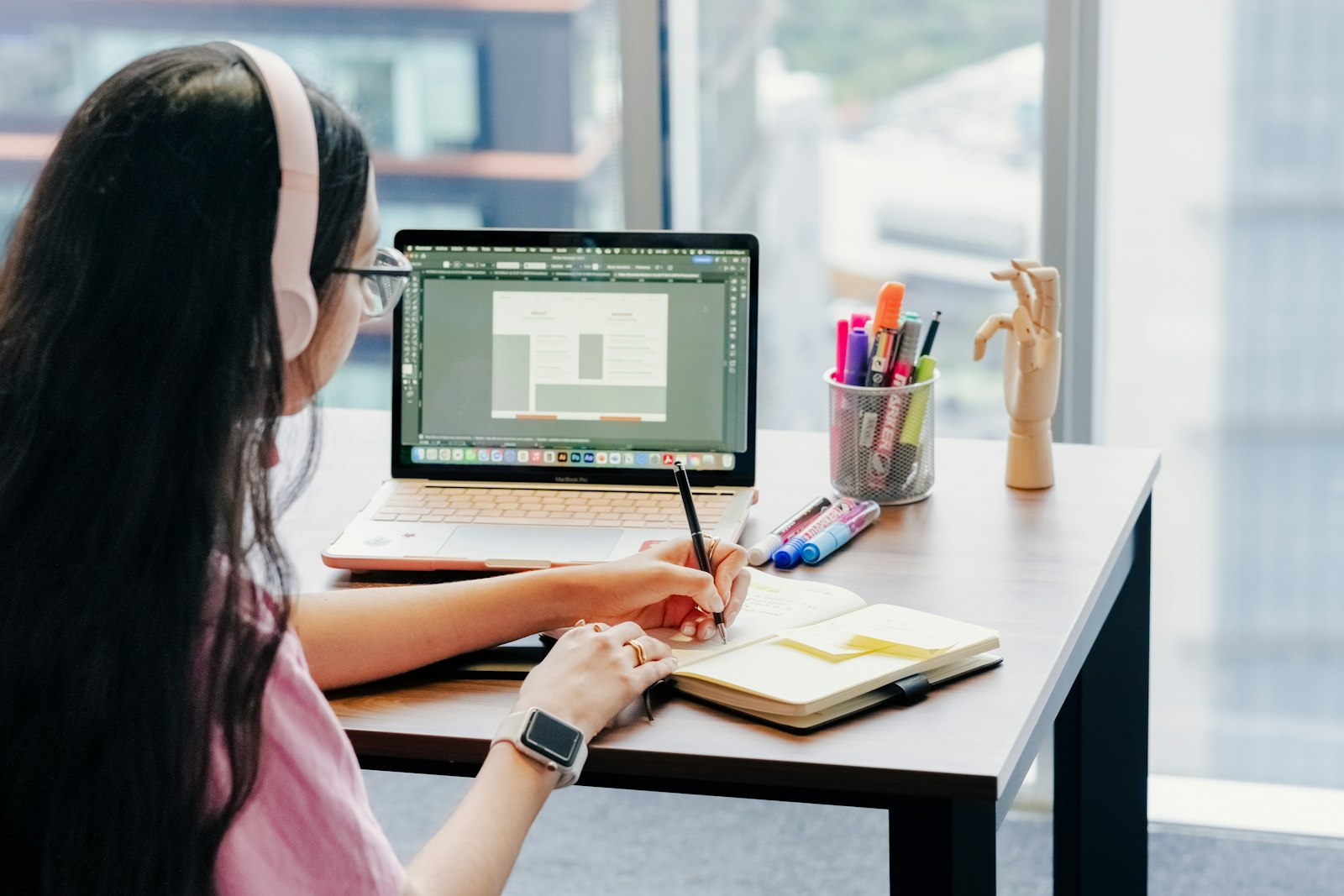 Frau mit Kopfhörern lernt am Schreibtisch – E-Learning-Entwicklung für flexible Mitarbeiterschulungen