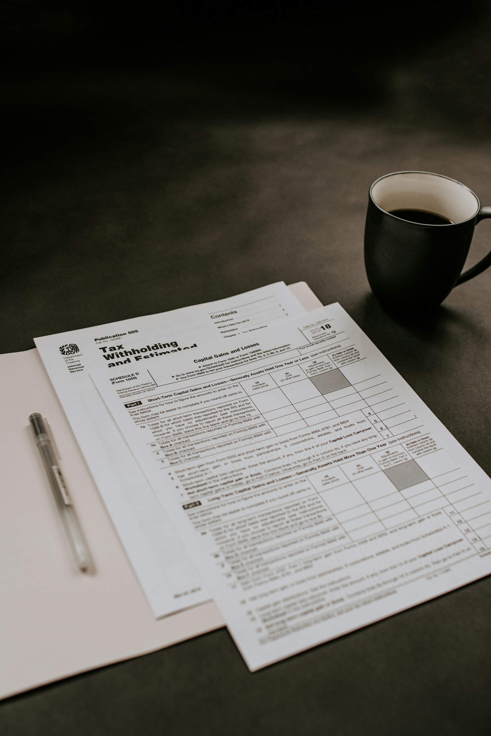 Kaffeebecher neben Druckerpapier auf dem Schreibtisch, Unterlagen zur Umsatzsteuer ID