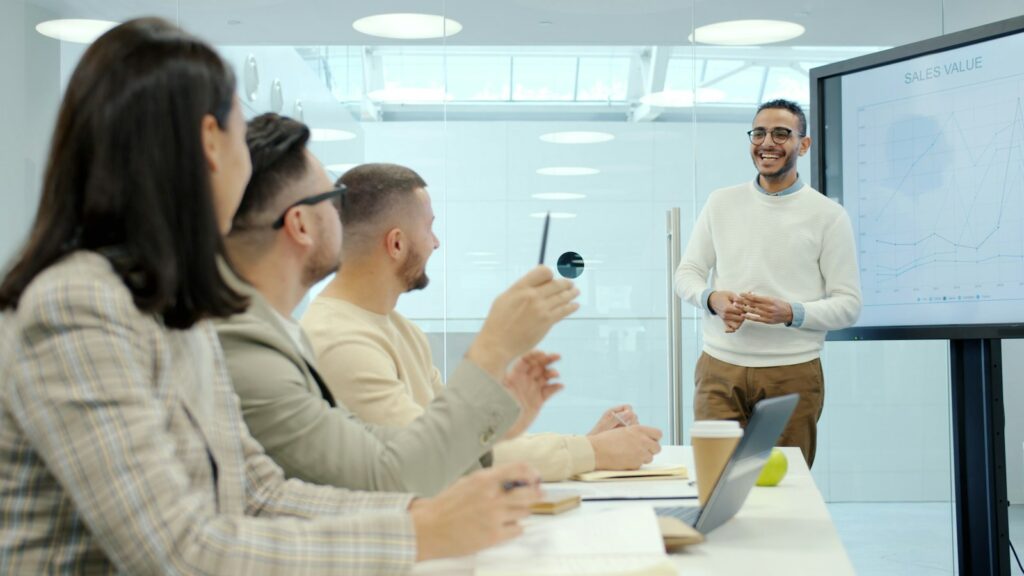 Mann präsentiert Kolleginnen und Kollegen in einem modernen Büro neue Schulungsinhalte