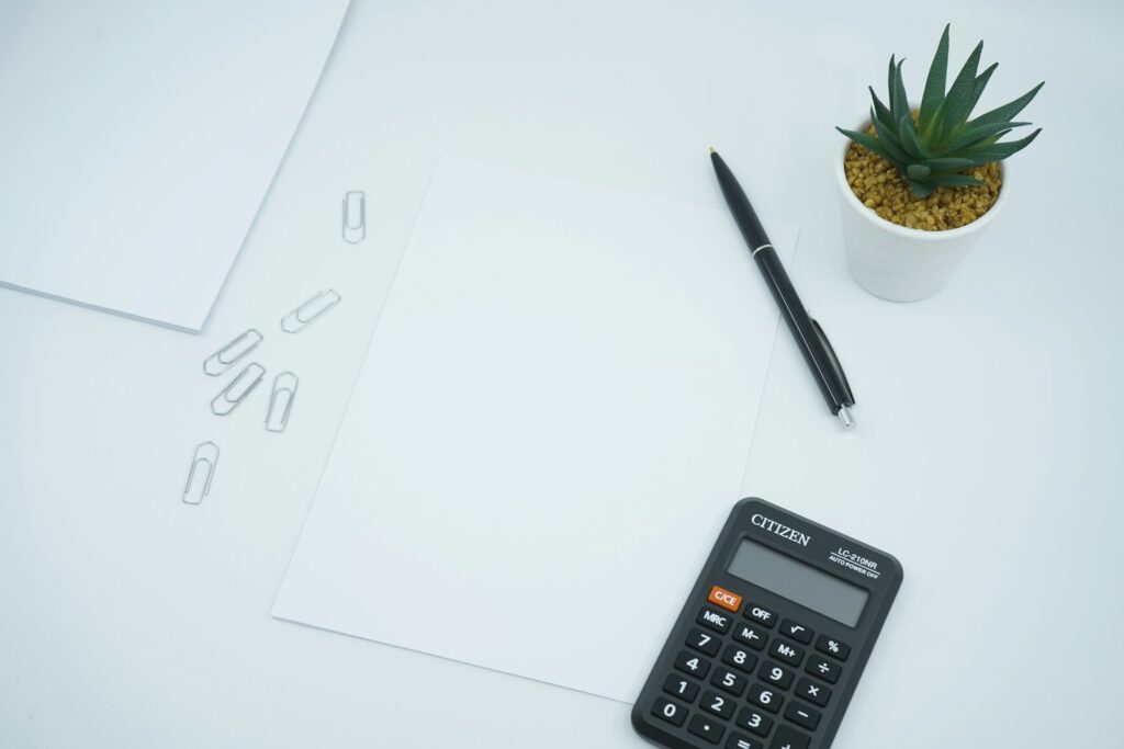 Rechnung schreiben: Taschenrechner und Stift auf weißem Papier