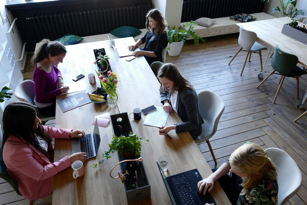 Team sitzt gemeinsam an einem Holztisch, Beispiel für Benefits für Mitarbeiter wie Essenszuschuss und Teamevents